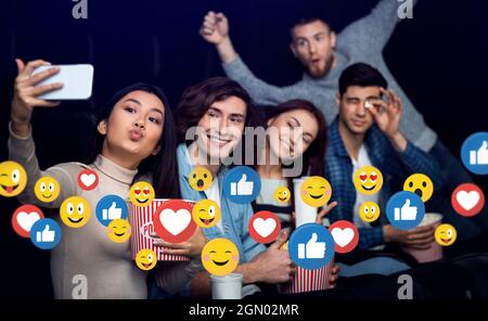 Fröhliche junge multirassische Freunde auf Party oder Theater mit Popcorn machen Selfie auf dem Smartphone Stockfoto