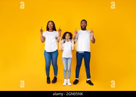 Überraschte schwarze Familie, die auf den Kopierraum im Studio zeigte Stockfoto