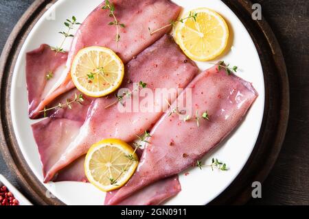 Frische Tintenfische oder Tintenfische für gekochte Speisen. Frischer roher Tintenfisch. Roher Tintenfisch mit Zitrone. Draufsicht und Kopierbereich für Ihren Text Stockfoto