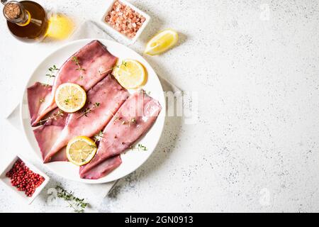 Frische Tintenfische oder Tintenfische für gekochte Speisen. Frischer roher Tintenfisch. Roher Tintenfisch mit Zitrone. Draufsicht und Kopierbereich für Ihren Text Stockfoto