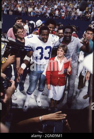 Dallas Texas USA, 1984: Die olympische Goldmedaillengewinnerin Mary Lou Retton, die während der Sommerspiele 1984 in Los Angeles für ihre Olympia-Heldinnen geehrt wurde, posiert mit Dallas Cowboys, die vor einem Cowboys-Spiel Tony Dorsett im Texas Stadium zurücklaufen. ©Bob Daemmrich Stockfoto