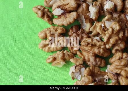 Draufsicht auf geschälte Walnüsse auf einem leuchtend grünen Tischtuch. Naturkost gesunde Snacks Hintergrund, mit Copyspace auf der linken Seite. Stockfoto