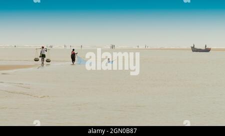 TAJPUR, WESTBENGALEN, INDIEN - 22. JUNI 2014 : Ein Fischer, der mit seiner Frau und seinem Sohn Fische mit Fischernetz am Ufer der Bucht von Bengalen fängt. Angeln Stockfoto