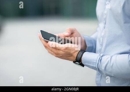 Nicht erkennbarer Geschäftsmann hält modernes Smartphone mit leerem Bildschirm, Nachbau Stockfoto