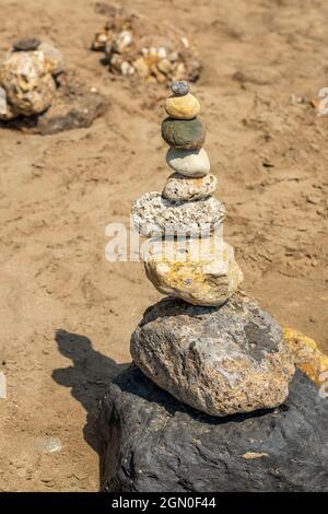 Steinhaufen oder Steine übereinander auf einem Strand in zakynthos griechenland. Turm aus Felsen am Strand in der Sommersonne. Stockfoto
