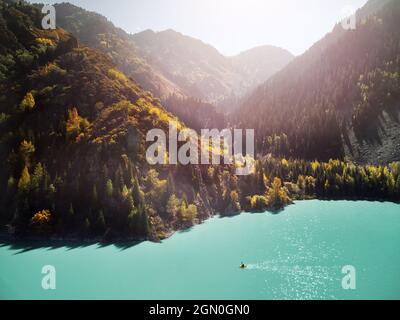 Im Herbst paddelt der Mensch auf einem gelben Floßboot im Bergsee. Luftdrohnenaufnahme. Stockfoto