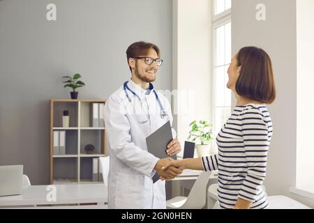 Der Arzt schüttelt die Hände als Zeichen der Begrüßung und Bekanntschaft mit einer Patientin im Krankenhaus. Stockfoto