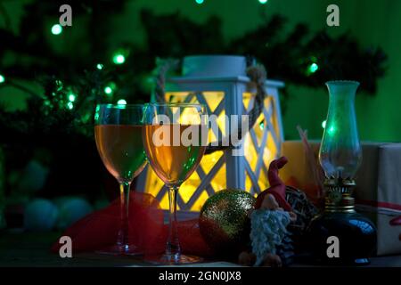 Weingläser in der Nähe von weihnachtsbaum und Laterne - Geschenke bereit, um das neue Jahr Freude zu bringen. Grünes Licht Stockfoto