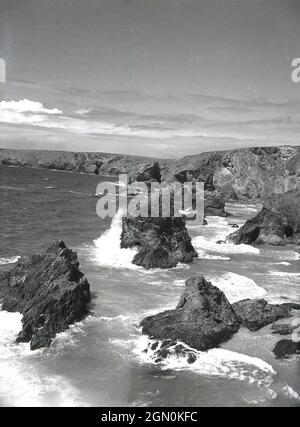 Die zerklüftete, felsige Küste von Land's End, Cornwall, im äußersten Südwesten Englands, Großbritannien, wurde in den 1950er Jahren historisch. Die Landzunge besteht aus Granit, der über Jahrhunderte abgebaut wurde und riesige Felsbrocken im umliegenden Ozean hinterlässt. Stockfoto