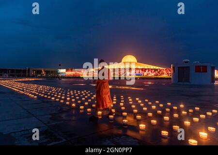 Patum Thani, Pathum Thani, Thailand. September 2021. Wat Dhammaya, bekannt für seine einzigartige Tempelkonstruktion und spirituelle Lehre, hielt eine Zeremonie anlässlich des Internationalen Tages des Friedens ab, der 1981 von den Vereinten Nationen als Tag der Waffenruhe und Gewaltlosigkeit gegründet wurde. Der Tempel organisierte eine Ausstellung von über 200,000 Kerzen und LED-Lichtern, um vom Himmel aus sichtbare Muster zu bilden, die verschiedene Phasen im Leben des verstorbenen Meditationsmeisters Luang Pu Sodh Candasaro des Tempels darstellen. Tausende von Menschen nahmen per Zoom-Anruf aus der Ferne an der Zeremonie Teil, wobei ihre Video-Feeds auf l angezeigt wurden Stockfoto