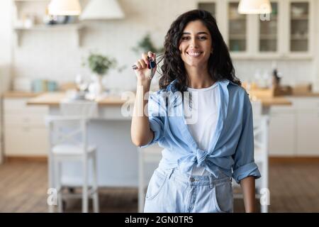 Neuer Hausbesitzer. Glückliche junge kaukasische Frau, die Wohnungsschlüssel hält, Haus kauft oder mietet, Platz kopiert Stockfoto