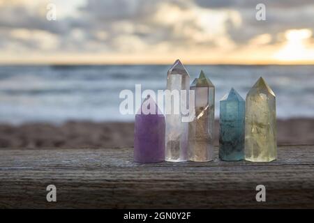 Heilende Reiki Kristalle auf Holz mit Meer bei Sonnenuntergang Hintergrund. Heilende Steine am Meer. Stockfoto