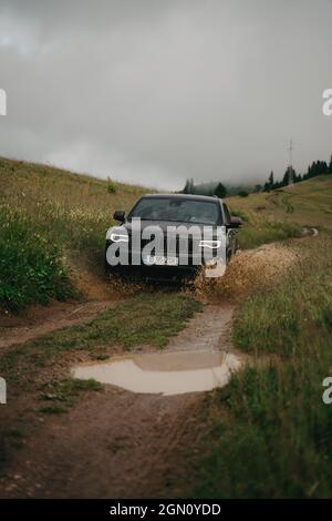 Ein Geländewagen, der durch eine Schlammpfütze in einer Offroad-Umgebung fährt Stockfoto