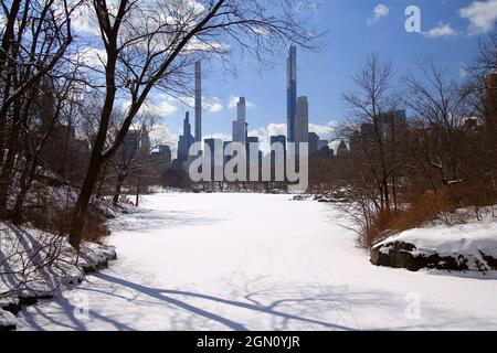 Die spektakulären Wolkenkratzer der Milliardärsreihe hinter dem verschneiten See des Central Park in New York City Stockfoto