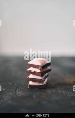 Selektive Konzentration auf vier Schokoladenscheiben auf dunklem Hintergrund. Stockfoto