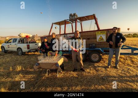 Kappadokien, Türkei - 14. September 2021: Arbeiter, die wie ein Heißluftballon-Pilot operieren, eröffnen Champagner nach einer sicheren Landung, um die Landung zu feiern Stockfoto
