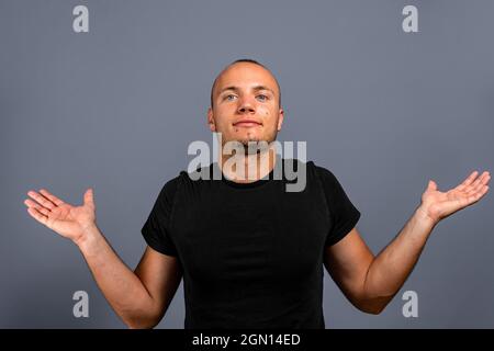 Ich weiß es nicht. Porträt von verwirrt gut aussehenden jungen Mann in blauen Casual-Stil schwarzes Hemd Blick auf die Kamera mit Antwort. Indoor-Studio-Aufnahme, isoliert auf Stockfoto