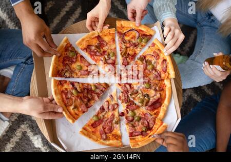 Draufsicht auf Freunde, die leckere Pizza mit Sasuages nehmen, Bier trinken, Party machen, abgeschnitten. Aufnahmen von Millennials, die schnell genießen Stockfoto