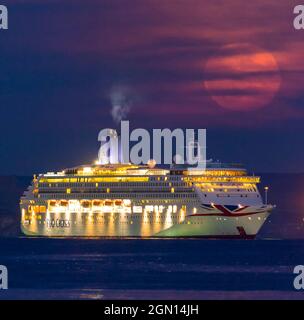 Weymouth, Dorset, Großbritannien. September 2021. Wetter in Großbritannien. Der volle Harvest Moon wird von dünnen hohen Wolken verdeckt, während er sich hinter dem P&O-Kreuzschiff Aurora erhebt, das am letzten Tag des astronomischen Sommers in der Bucht von Weymouth in Dorset an der Küste verankert ist. Bildnachweis: Graham Hunt/Alamy Live News. Stockfoto