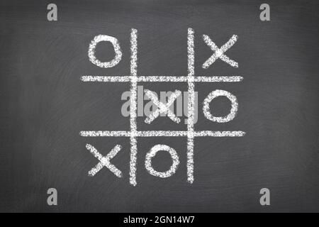 Ein Spiel mit Tic tac toe, das auf einem Kreidetafel gespielt wird, zeigt die Notwendigkeit, ein kritischer Denker in der Welt des Spielens zu sein. Stockfoto