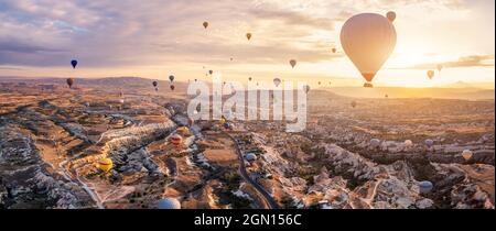 Heißluftballons fliegen über Göreme, Kappadokien (Kapadokya) Anatolien, Türkei bei Sonnenaufgang. Panoramablick auf Dörfer und Feenkamine. Beliebte Touri Stockfoto
