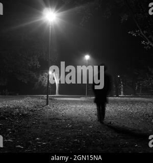 Surrealer Mann, der nachts im Park spazieren geht. Stockfoto