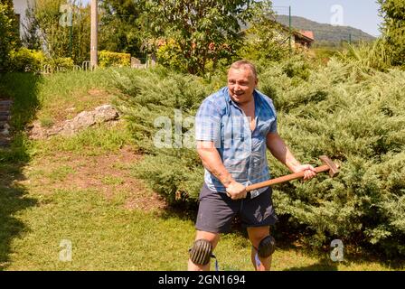 Muskulöser reifer Mann mit Hammer im Garten. Stockfoto