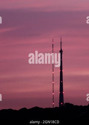 Emley Moor Sending Station, in Wakefield, West Yorkshire, stellte sich vor einem violetten Sonnenuntergang. Links ist der temporäre Turm, rechts ist der Arqiva zu Stockfoto