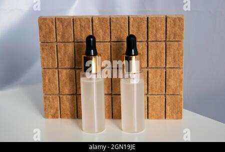 Zwei Flaschen mit Pipetten auf braunem Hintergrund. Serum, ätherische Öle oder flüssiges Kollagen, Hautpflegekonzept. Stockfoto