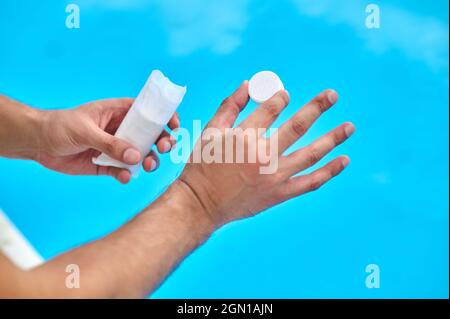 Vorbereitung zur Schwimmbaddesinfektion mit Chlortabletten Stockfoto