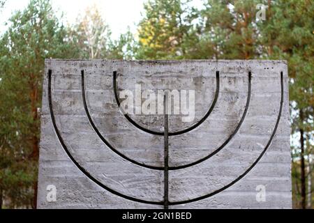 Defokussieren Sie das Menorah-Symbol auf Betonplatten in Wald und Natur. Symbole des jüdischen Volkes. Erinnerung und Ehrfurcht.außer Fokus Stockfoto