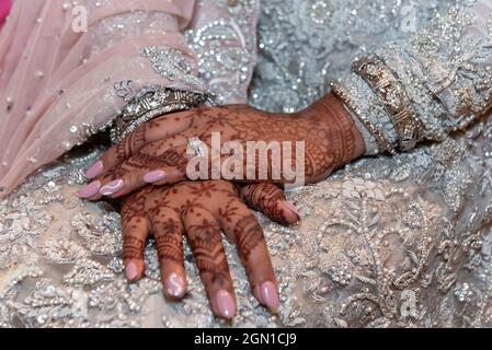 Die schönen Hände der Hindu-Braut sind mit traditioneller Mehndi Henna-Tattoo-Kunst, Maniküre und Diamantring verziert. Stockfoto