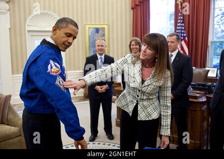 Janet Kavandi, Director of Flight Crew Operations am Johnson Space Center, überreicht Präsident Obama während eines Abflugs mit der Crew des Space Shuttle Atlantis im Oval Office am 1. November 2011 eine Jacke. Die Jacke verfügt über Patches aus mehreren vergangenen Space-Shuttle-Missionen. Im Hintergrund von links sind: Pilot Doug Hurley, Missionsspezialist Sandy Magnus, Kommandant Chris Ferguson und Missionsspezialist Rex Walheim zu sehen. (Offizielles Foto des Weißen Hauses von Pete Souza) Dieses offizielle Foto des Weißen Hauses wird nur zur Veröffentlichung durch Nachrichtenorganisationen und/oder für Personen zur Verfügung gestellt Stockfoto