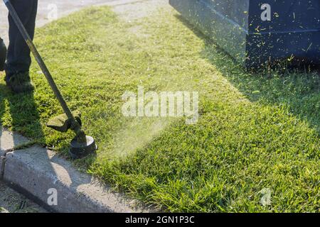 Nahaufnahme der Schnur-Trimmerkopf-Unkrautfräse-Motorsense, die im Garten Gras schneidet Stockfoto