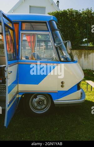 Vertikale Aufnahme eines blauen Oldtimers, der an einem sonnigen Tag in einem Garten geparkt ist Stockfoto