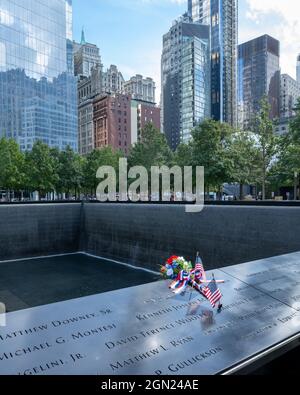 New York, USA, 21. September 2021 - US-Flaggen und Blumen sind neben den Namen der Opfer des Terroranschlags auf der National September 11 Memoria zu sehen Stockfoto