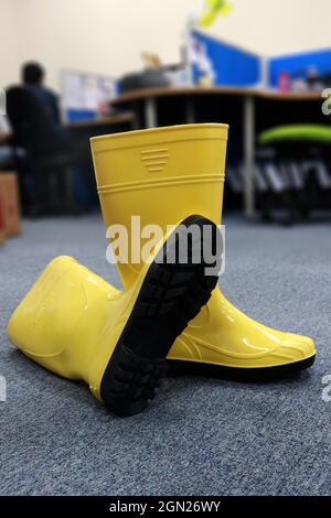 Ein Paar gelbe Stiefel aus Gummi, die von Arbeitern für die Gartenarbeit und alle Aktivitäten an nassen Orten verwendet werden, um die Füße vor Schmutz und schädlichen Chemikalien zu schützen Stockfoto