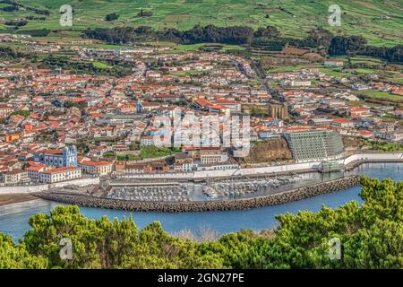Überblick von oben über die bunten Gebäude des historischen Angra do Heroismo, den Yachthafen und das grüne Ackerland von Monte Brasil, Terceira und den Azoren. Stockfoto