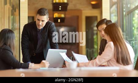 In einem modernen Besprechungsraum treffen sich verschiedene Geschäftsleute, um Geschäftsideen zu diskutieren und zu Brainstorming zu führen Stockfoto