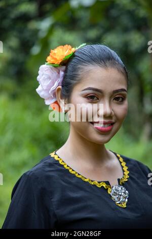 Porträt einer fröhlichen jungen Frau in traditioneller Tracht im Sarawak Kulturdorf, nahe Kuching, Sarawak, Borneo, Malaysia, Asien Stockfoto
