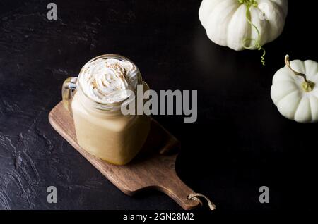 Halloween-Getränk. Köstlicher Kaffee-Latte im Glas, Creme und Kürbis auf dunkle Weise. Stockfoto