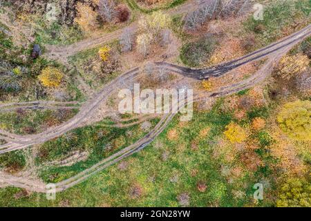Herbstliche Naturlandschaft und Straßen durch die sumpfigen Felder mit Pfützen und Schlamm. Drohnenfoto. Stockfoto
