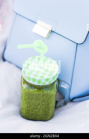 Gesunder grüner Smoothie in einem Becher mit Spinat, Kiwi, Banane und Apfel auf einem Holzboden Stockfoto