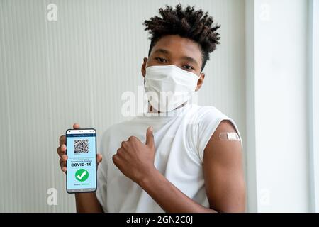 Afroamerikanischer Teenager zeigt Impfpass auf dem Handy, um die Reisegenehmigung durch das digitale Dokument zu validieren Stockfoto