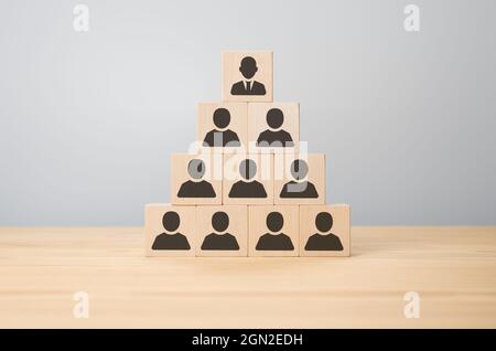 Business Executive stapelt Holzwürfel mit Menschen Symbole auf ihnen in Pyramide. Personalwesen, Unternehmenshierarchie und mehrstufiges Marketingkonzept. M Stockfoto