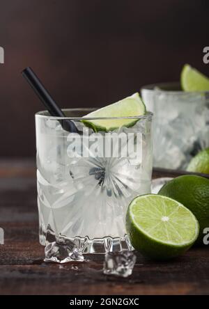 Gimlet Kamikaze Cocktail in Kristallglas mit Limettenscheibe und Eis auf Holzhintergrund. Stockfoto