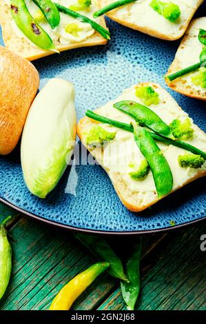 Gemüsebruschetta mit Brokkoli, grünen Erbsen und Spargelbohnen.Vegetarisches Essen Stockfoto