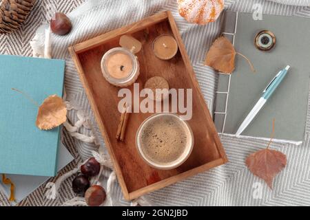 Hygge. Stillleben im Herbst mit Kaffee, Kerzen, Herbstblättern, einem Tagebuch und einigen Büchern, Flachschuss über dem Kopf Stockfoto