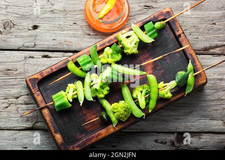Gemüsekebab mit Brokkoli, grünen Erbsen und Okra auf Küchenbrett.Gebratenes Gemüse auf einem Spieß Stockfoto