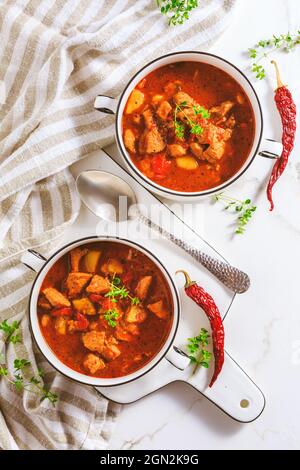 Rindergulaschsuppe – herzhafte ungarische Suppe mit Fleisch und Gemüse, gewürzt mit Paprika auf weißem Hintergrund Stockfoto